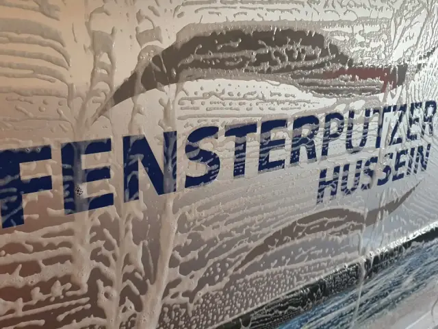 Firmenschriftzug „Fensterputzer Hussein“ unter Reinigungsschaum